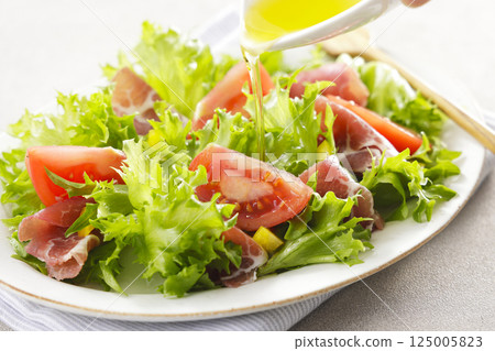 Tomato, prosciutto and leaf lettuce salad 125005823