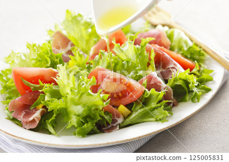 Tomato, prosciutto and leaf lettuce salad 125005831