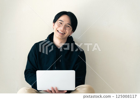 Man using a computer by the wall Man using a computer by the wall 125008117
