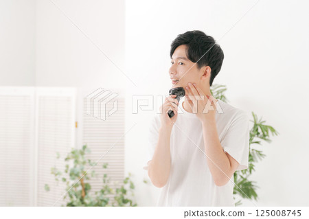 A young man shaving his beard A young man shaving his beard 125008745