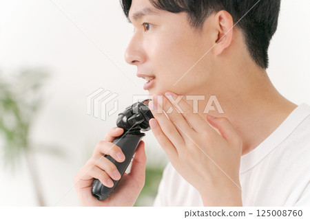 A young man shaving his beard 125008760
