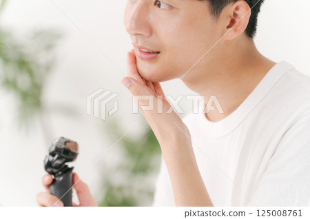 A young man shaving his beard 125008761
