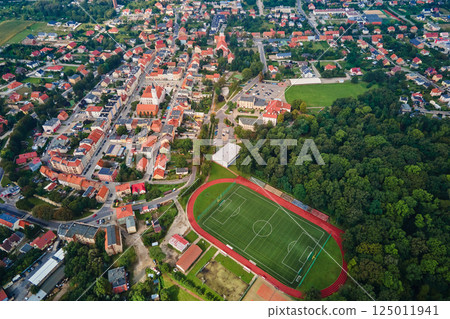 Aerial view of small European town with red roof houses, football field and green park on sunny day 125011941