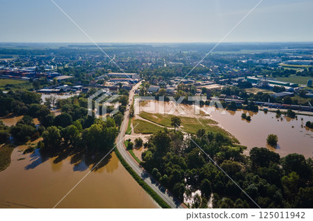 Aerial view of flooded streets, railway tracks and buildings in a suburban area. Industrial zone with floodwater after heavy rain. Concept of natural disaster, climate impact and emergency Aerial view of flooded streets, railway tracks and buildings in a suburban area. Industrial zone with floodwater after heavy rain. Concept of natural disaster, climate impact and emergency 125011942