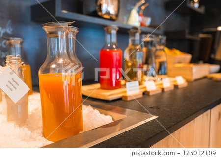 Selection of drinks in glass carafes, including orange juice on ice, on a black countertop with wooden accents in a modern luxury hotel in the Italian Alps. Selection of drinks in glass carafes, including orange juice on ice, on a black countertop with wooden accents in a modern luxury hotel in the Italian Alps. 125012109