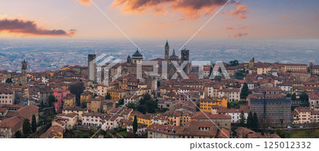 View of Bergamo's old town, Italy, at sunset, featuring the Basilica of Santa Maria Maggiore, medieval bell towers, and terracotta rooftops. 125012332