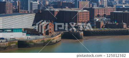 Aerial view of Liverpool showcasing Albert Dock's red brick warehouses, the Museum of Liverpool, the Mersey River, and a mix of historic and modern buildings. 125012382