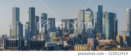 Panoramic view of Canary Wharf in London, showcasing One Canada Square and other skyscrapers surrounded by residential and commercial buildings. 125012414