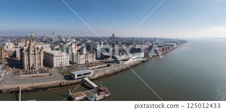 Aerial view of Liverpool showcasing the Royal Liver Building, Cunard Building, Port of Liverpool Building, Museum of Liverpool, and the Mersey River. 125012433