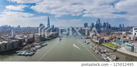 Aerial view of London featuring Tower Bridge over the River Thames, The Shard, Canary Wharf, and historic and modern riverside architecture on a bright day. Aerial view of London featuring Tower Bridge over the River Thames, The Shard, Canary Wharf, and historic and modern riverside architecture on a bright day. 125012495