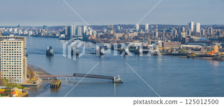 Aerial view of the Thames Barrier on the River Thames in London, surrounded by modern buildings and high rise structures on a clear day. 125012500