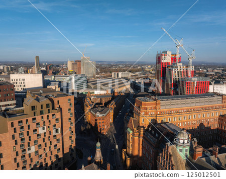 Aerial view of Manchester, UK, on a sunny day with the Manchester Central Convention Complex, modern skyscrapers, and ongoing construction visible. 125012501