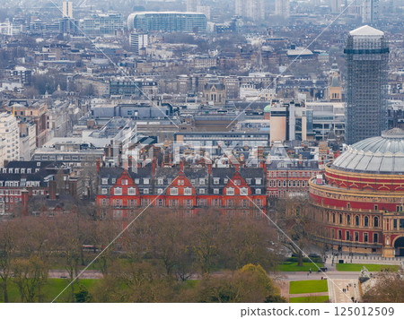 Aerial view of London with the Royal Albert Hall on the right, bare trees in the foreground, red brick buildings, and modern high rises in the distance. Aerial view of London with the Royal Albert Hall on the right, bare trees in the foreground, red brick buildings, and modern high rises in the distance. 125012509