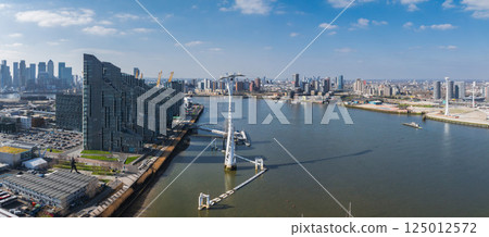 Aerial perspective of London featuring the River Thames, Canary Wharf skyscrapers, Emirates Air Line cable cars, and urban architecture under clear skies. 125012572