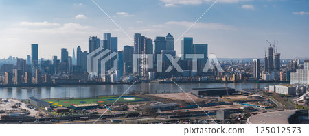 Aerial view of London's Canary Wharf skyline with modern skyscrapers, the River Thames in the foreground, and the Shard visible in the distance. Aerial view of London's Canary Wharf skyline with modern skyscrapers, the River Thames in the foreground, and the Shard visible in the distance. 125012573