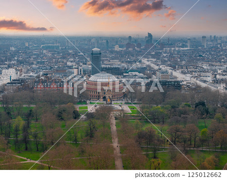 Aerial view of London's Royal Albert Hall with its domed roof, the Albert Memorial, surrounding parkland, and urban architecture under a cloudy sky. Aerial view of London's Royal Albert Hall with its domed roof, the Albert Memorial, surrounding parkland, and urban architecture under a cloudy sky. 125012662
