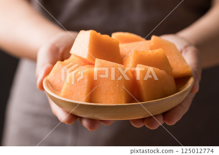 Sliced Orange melon, Musk melon or Flesh melon on plate holding by hand ready to eating Sliced Orange melon, Musk melon or Flesh melon on plate holding by hand ready to eating 125012774