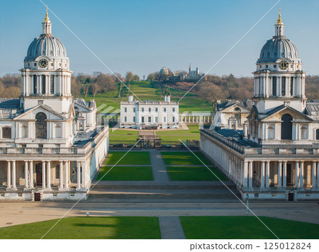 The Old Royal Naval College's twin domes flank a pathway, with the Queen's House and Royal Observatory on Greenwich Park hill under a clear blue sky. The Old Royal Naval College's twin domes flank a pathway, with the Queen's House and Royal Observatory on Greenwich Park hill under a clear blue sky. 125012824