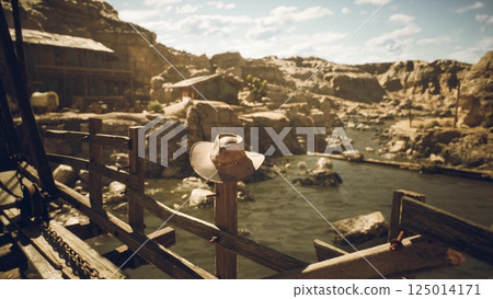 A rustic hat resting on a wooden fence near a serene river in the wilderness A rustic hat resting on a wooden fence near a serene river in the wilderness 125014171