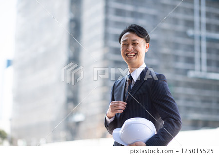 Businessman standing outside a construction site 125015525