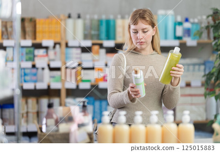 Young woman client choosing shampoo in drugstore Young woman client choosing shampoo in drugstore 125015883