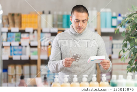 Man choose painkiller pills box in pharmacy 125015976