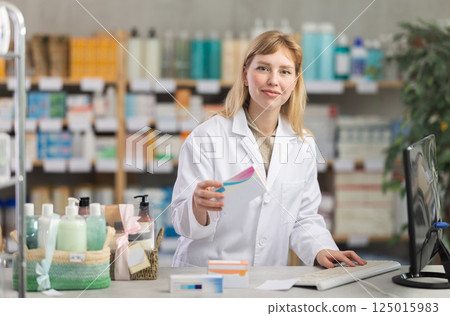 Female pharmacist standing at drugstore with medical product in hands 125015983