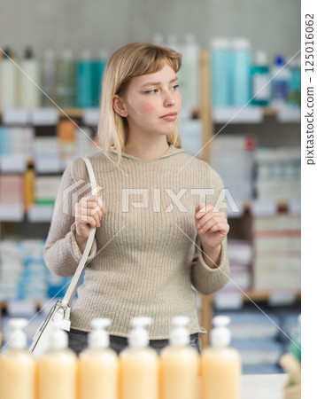 Portrait of girl in autumn clothes shopper choosing some products in supermarket 125016062
