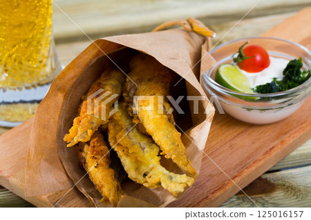 Fish and chips with creamy cheese sauce 125016157