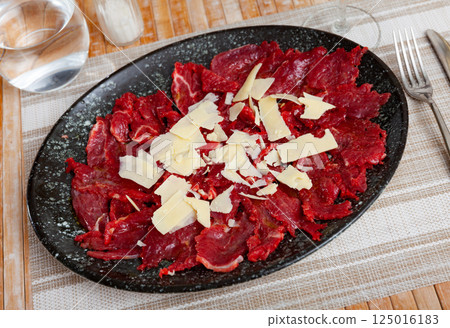 Beef carpaccio cold appetizer with parmesan, on plate 125016183