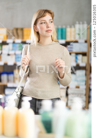Portrait of girl in autumn clothes shopper choosing some products in supermarket Portrait of girl in autumn clothes shopper choosing some products in supermarket 125016305