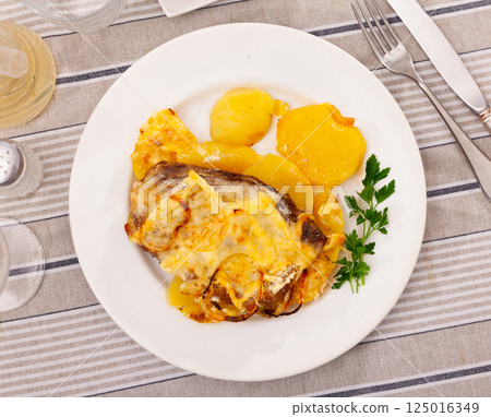 Pork steaks and potatoes baked with onions and cheese 125016349