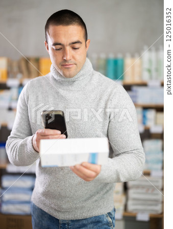 Man scans code on package of ointment to check expiration date 125016352