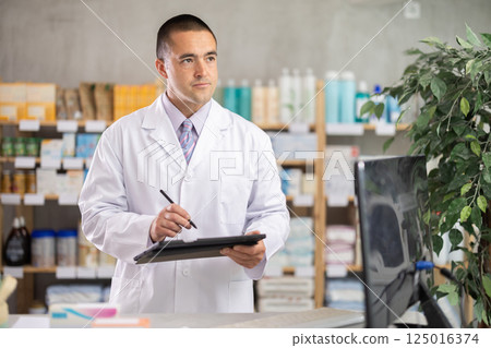 Male pharmacist conducting inventory with tablet 125016374