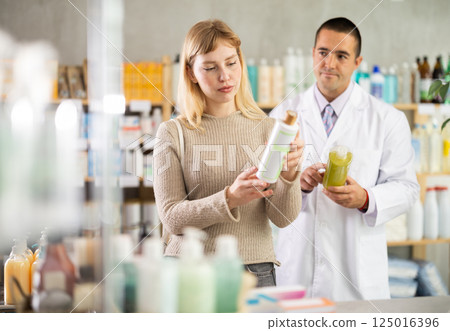 woman chooses a shampoo against the background of a pharmacist woman chooses a shampoo against the background of a pharmacist 125016396