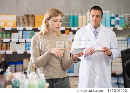Woman chooses pills against the background of a male pharmacist Woman chooses pills against the background of a male pharmacist 125016410