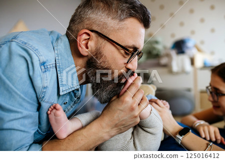 Portrait of father kissing little baby boy's feet. Portrait of father kissing little baby boy's feet. 125016412