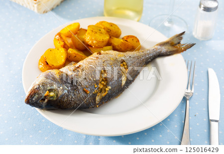 Baked fish called Dorada with toasted potatoes Baked fish called Dorada with toasted potatoes 125016429