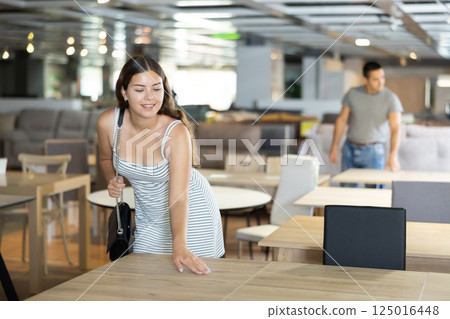 In furniture showroom,woman inspects sliding kitchen table In furniture showroom,woman inspects sliding kitchen table 125016448