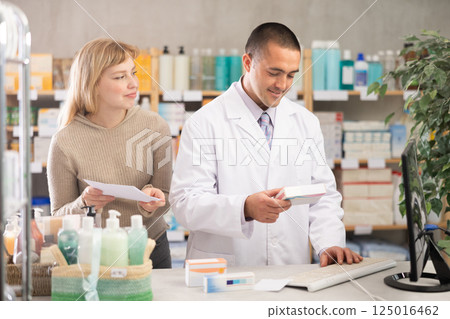 Man pharmacist is working at computer, communicate with girl customer 125016462