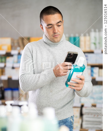 Male buyer scans code on mouthwash to check expiration date 125016514