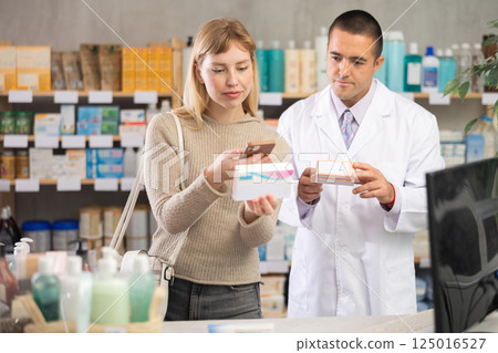 Young woman scanning QR-code on pills box while pharmacist offering Young woman scanning QR-code on pills box while pharmacist offering 125016527