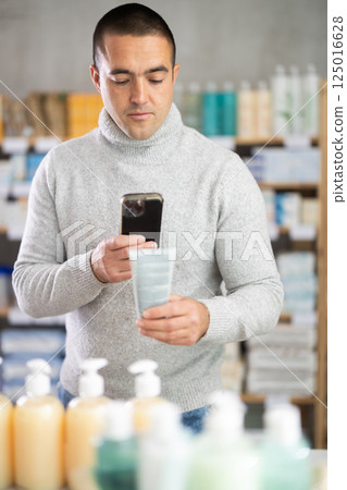 Man in pharmacy scans QR code on emollient for sensitive skin 125016628