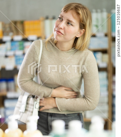 Woman with PMS spasms in pharmacy Woman with PMS spasms in pharmacy 125016687