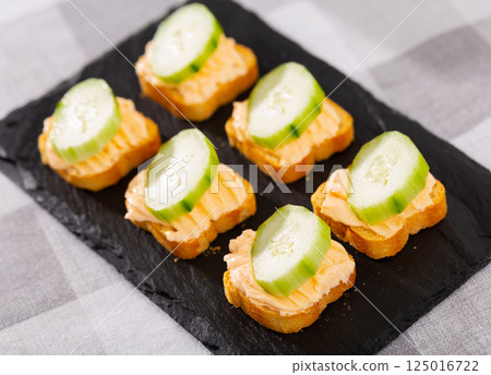 Simple homemade snack of sandwiches, greased with butter and decorated with slice of cucumber Simple homemade snack of sandwiches, greased with butter and decorated with slice of cucumber 125016722