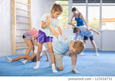 Boys and girls in gym perform basic elements of krav maga self-defense system. 125016732