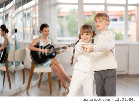 Boy and girl in pair train to dance tango during classes with accompaniment of guitar 125016843