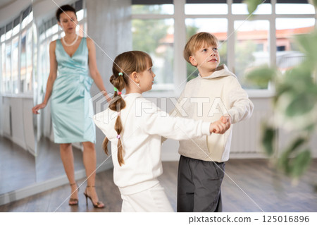 Boy with girl dressed in sport wear train to dance waltz during classes. 125016896
