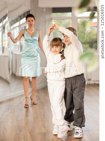 Boy with girl dressed in sport wear train to dance waltz during classes. 125016935