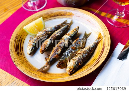 Deliciously fried many sardines served with lemon at plate Deliciously fried many sardines served with lemon at plate 125017089
